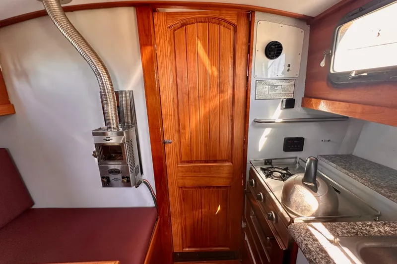 Slide: The Image of Cozy 1972 Fisher 30 boat interior with wood paneling, stove, and seating area. - 48