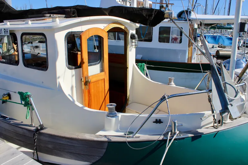 Slide: The Image of 1972 Fisher 30 sailboat with wooden door, docked in a marina under clear blue skies. - 5