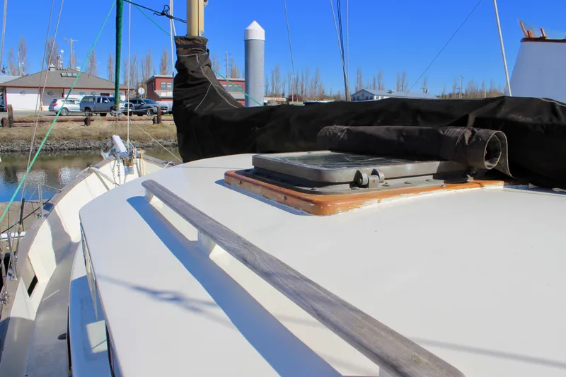 Slide: The Image of 1972 Fisher 30 sailboat deck with hatch, docked near buildings and vehicles. - 7