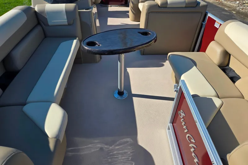 Slide: The Image of 2023 SunChaser Geneva Fish 22 pontoon boat interior with beige seating and central table. - 11