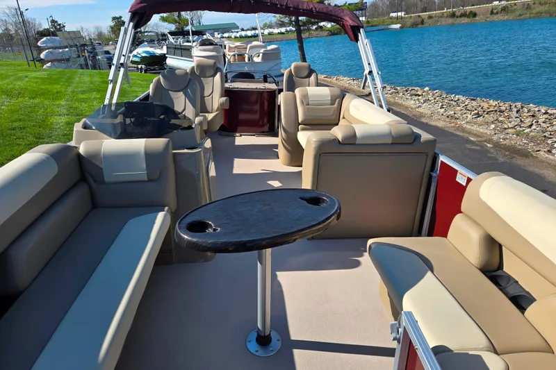 Slide: The Image of 2023 SunChaser Geneva Fish 22 pontoon boat interior with seating and table by the water. - 12