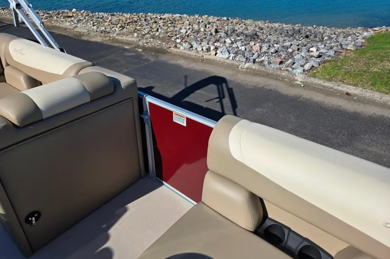Slide: The Image of 2023 SunChaser Geneva Fish 22 pontoon boat interior with beige seating by the water. - 13