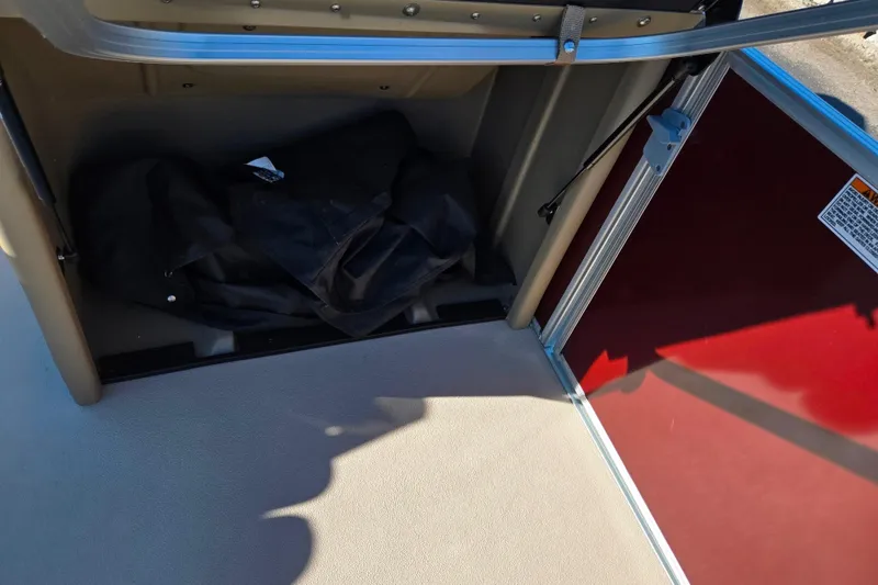 Slide: The Image of Storage compartment in 2023 SunChaser Geneva Fish 22 boat, featuring red panel and black bag. - 14