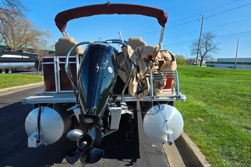 Slide: The Image of 2023 SunChaser Geneva Fish 22 pontoon boat with outboard motor, parked on grass. - 2