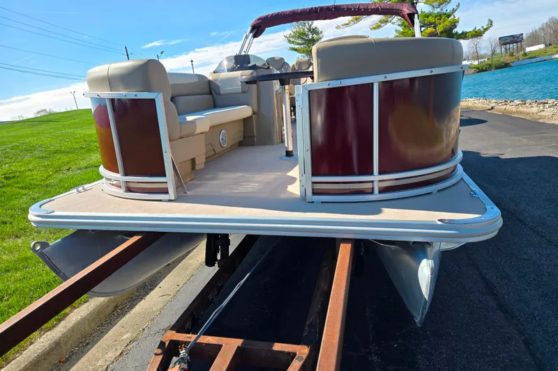 Slide: The Image of 2023 SunChaser Geneva Fish 22 pontoon boat on trailer by a lake. - 6