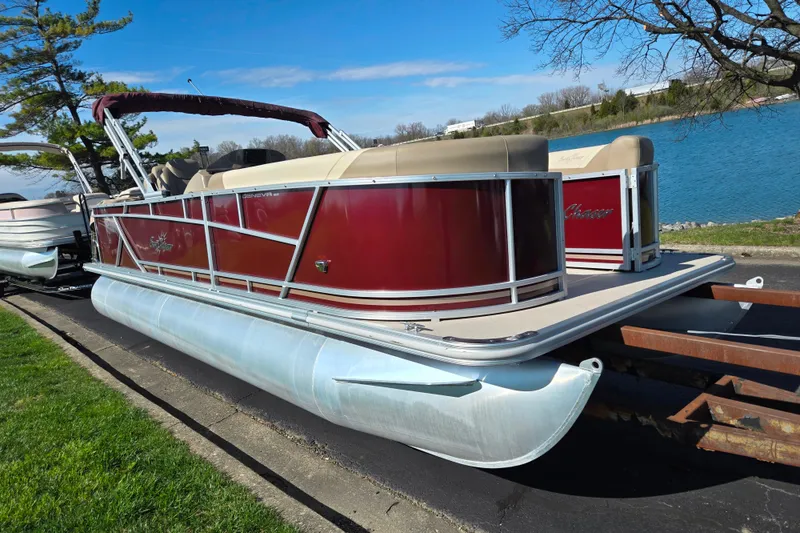 Slide: The Image of 2023 SunChaser Geneva Fish 22 pontoon boat on trailer by a lake. - 8