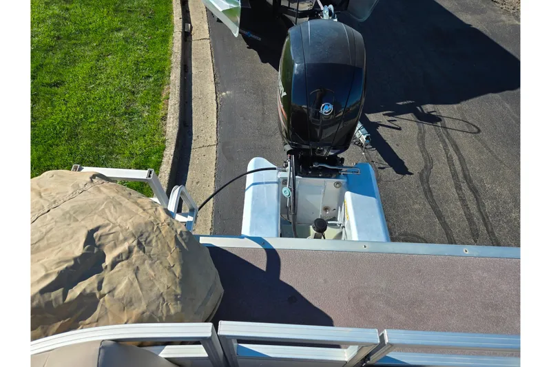 Slide: The Image of 2016 Sun Tracker Party Barge 24 DLX with outboard motor, parked on pavement. - 17