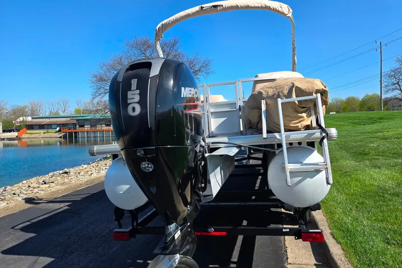 Slide: The Image of 2016 Sun Tracker Party Barge 24 DLX with Mercury 150 engine on trailer by a lake. - 2