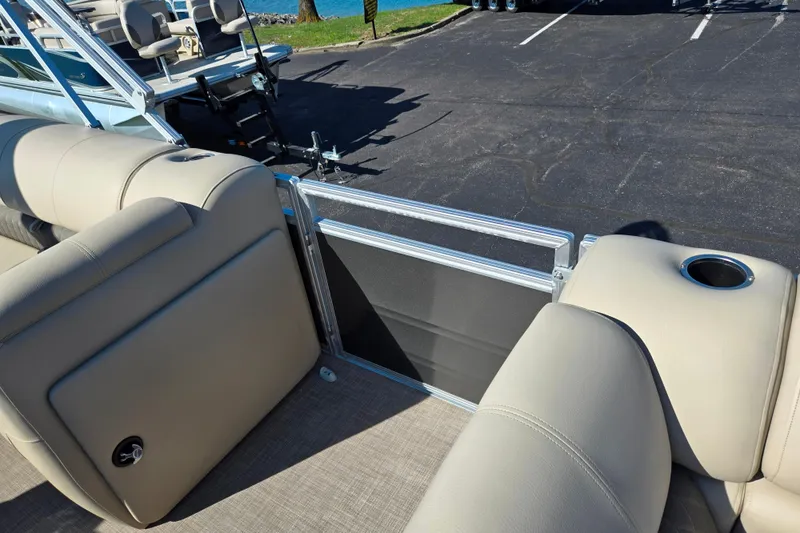 Slide: The Image of 2024 Sun Tracker Party Barge 20 DLX interior with beige seating and cup holder. - 12
