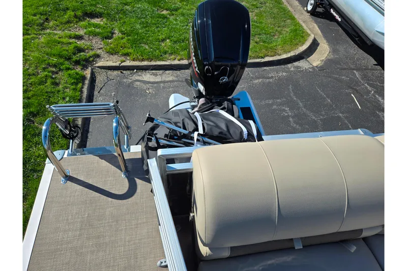 Slide: The Image of 2024 Sun Tracker Party Barge 20 DLX with motor and seating, parked on pavement. - 17