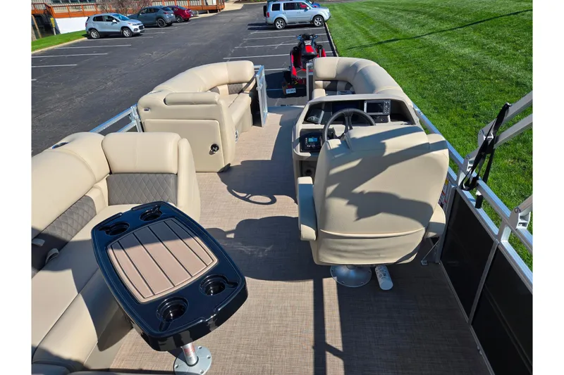 Slide: The Image of 2024 Sun Tracker Party Barge 20 DLX interior with beige seating and steering console. - 19