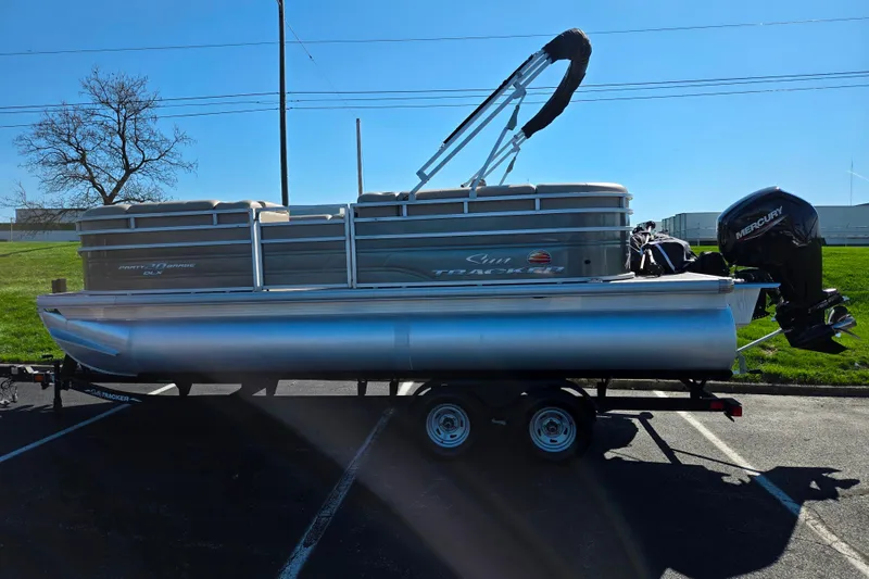 Slide: The Image of 2024 Sun Tracker Party Barge 20 DLX pontoon boat on trailer, parked outdoors. - 4
