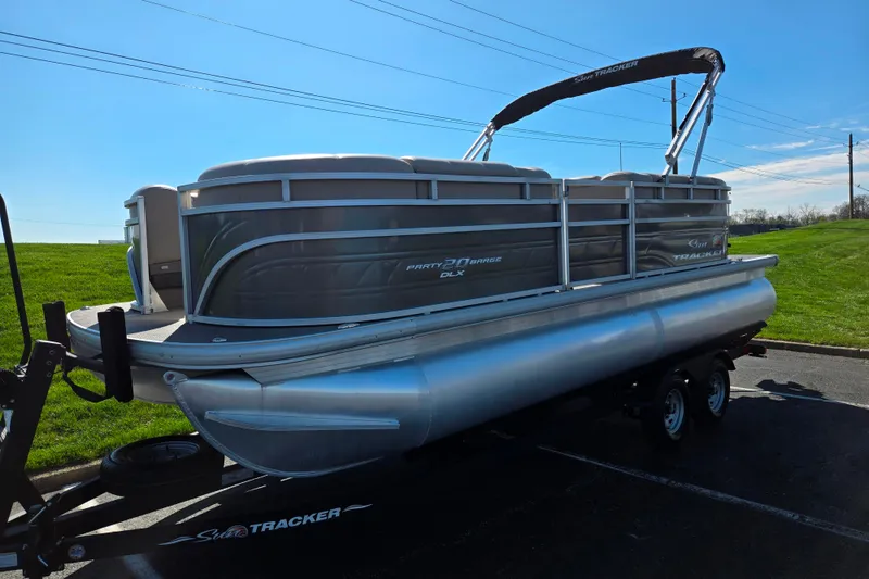 Slide: The Image of 2024 Sun Tracker Party Barge 20 DLX pontoon boat on trailer, parked outdoors. - 5