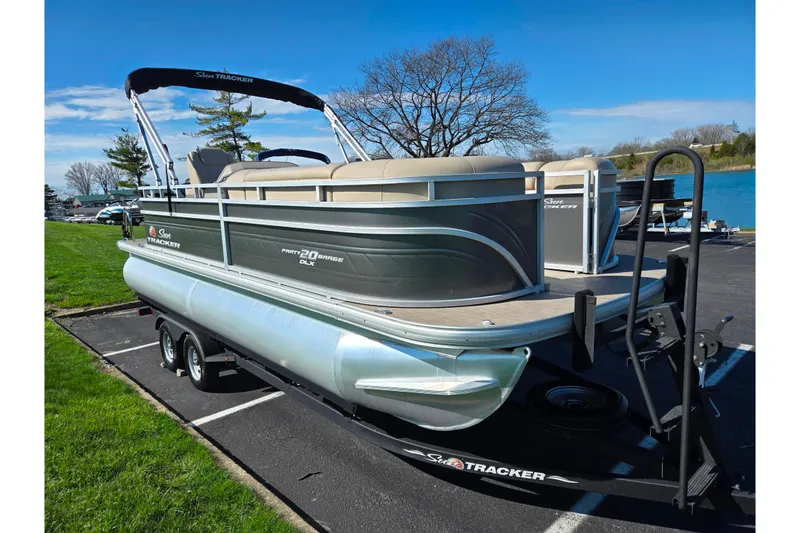 Slide: The Image of 2024 Sun Tracker Party Barge 20 DLX pontoon boat on trailer by a lake. - 8