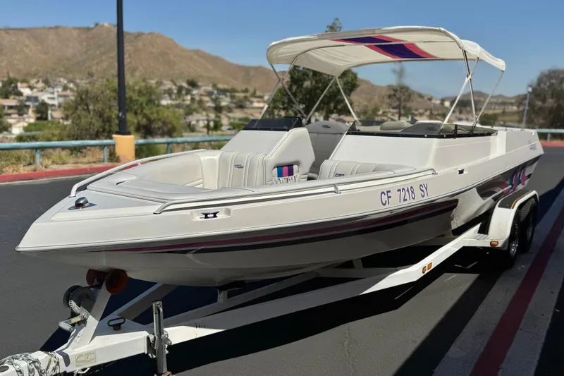 Slide: The Image of 1996 Warlock Ultimate boat on trailer, parked on road with scenic background. - 3