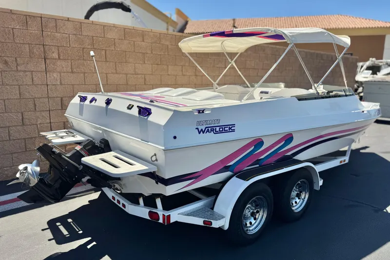 Slide: The Image of 1996 Warlock Ultimate boat with vibrant graphics and dual-axle trailer in a sunny setting. - 5