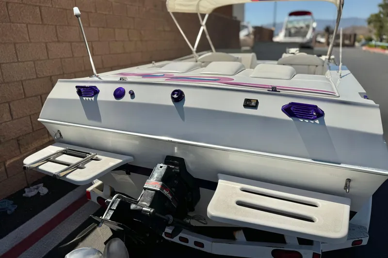 Slide: The Image of 1996 Warlock Ultimate boat with purple accents, parked on a trailer, rear view. - 6