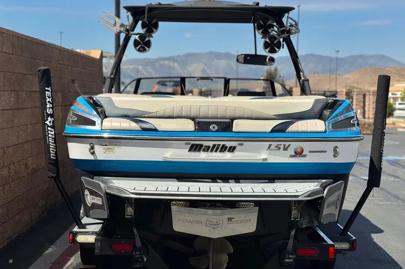 Slide: The Image of 2015 Malibu Wakesetter 247 LSV boat, rear view, parked outdoors with mountains in background. - 4