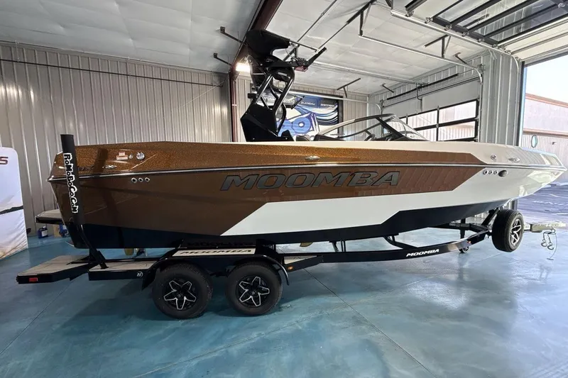 Slide: The Image of 2026 Moomba Max boat in showroom, brown and white design, on trailer. - 6