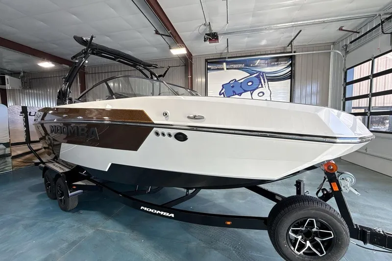 Slide: The Image of 2026 Moomba Max boat in showroom, white and brown design, on trailer. - 7