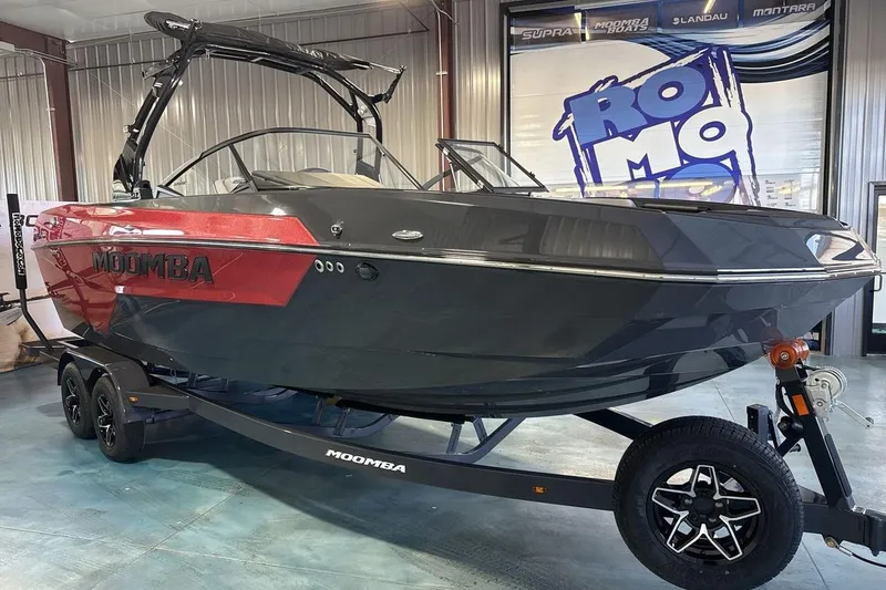 The Image of 2026 Moomba Tykon boat in showroom, featuring sleek black and red design on trailer. - 1