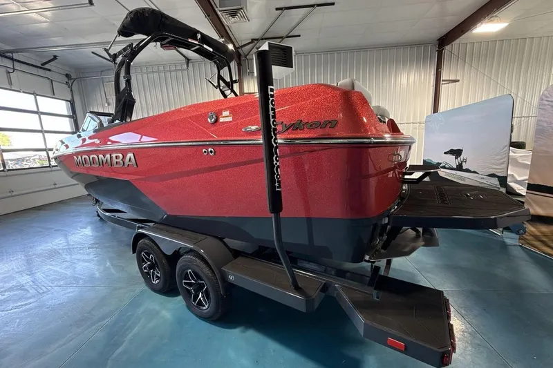 Slide: The Image of 2026 Moomba Tykon boat in showroom, red exterior, on trailer, indoor setting. - 4