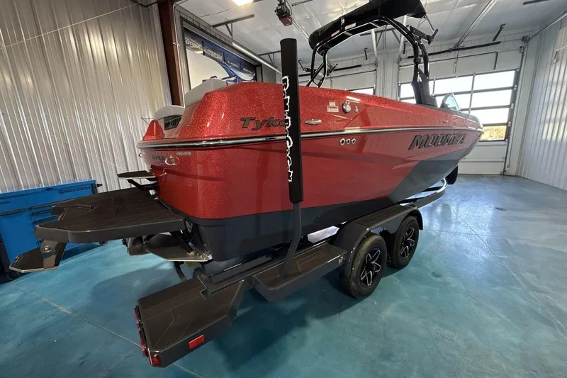 Slide: The Image of Red 2026 Moomba Tykon boat on trailer in a spacious indoor garage. - 6