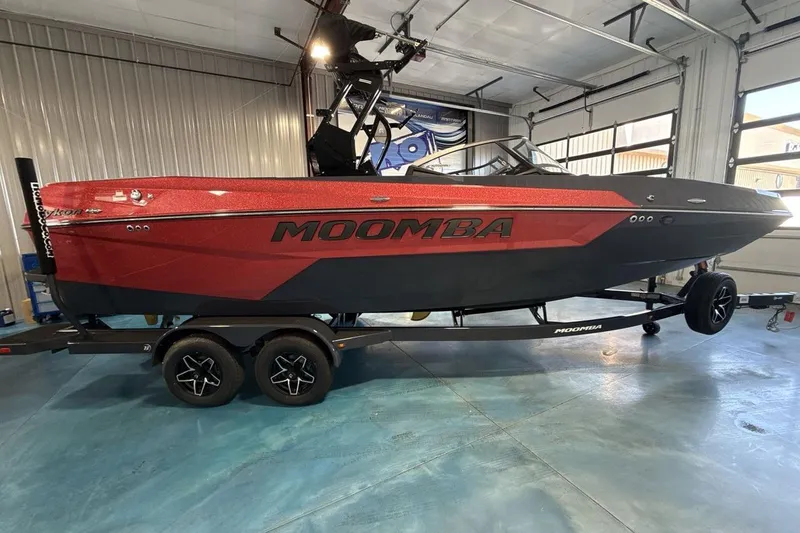 Slide: The Image of 2026 Moomba Tykon boat in a garage, featuring a sleek red and black design. - 7