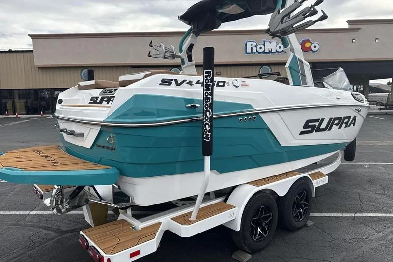 Slide: The Image of 2026 Supra SV boat on trailer, teal and white design, parked outdoors. - 5