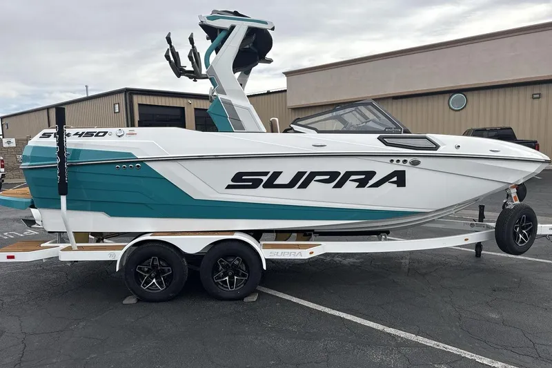 Slide: The Image of 2026 Supra SV boat on trailer, teal and white design, parked outdoors. - 6