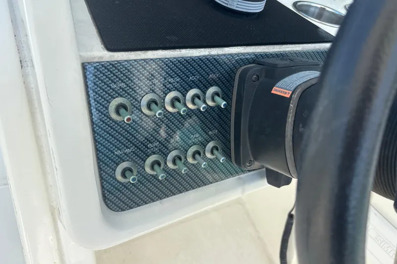 Slide: The Image of Control panel of a 2018 World Cat 230 SD boat with switches and steering wheel. - 17