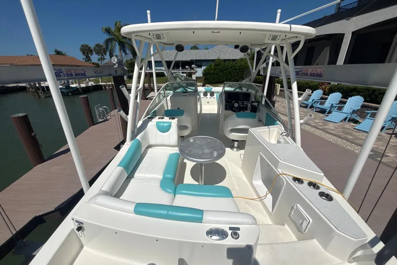 Slide: The Image of 2018 World Cat 230 SD boat interior with seating, table, and helm, docked by waterfront. - 21