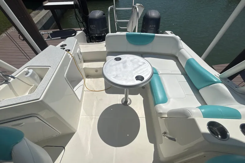 Slide: The Image of 2018 World Cat 230 SD boat interior with seating, table, and dual outboard motors. - 7