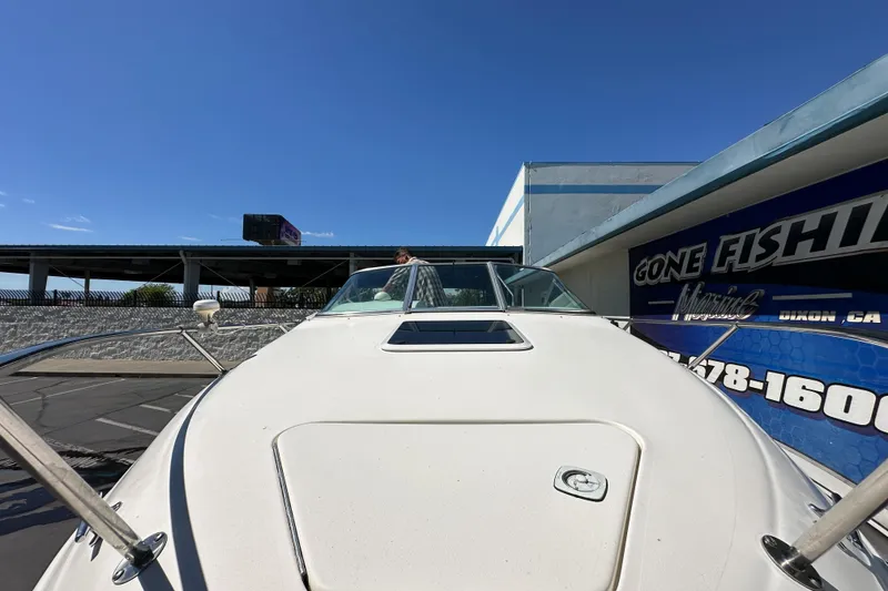 Slide: The Image of 1998 Sea Ray 215 Express Cruiser docked near a "Gone Fishing" sign under clear blue skies. - 4