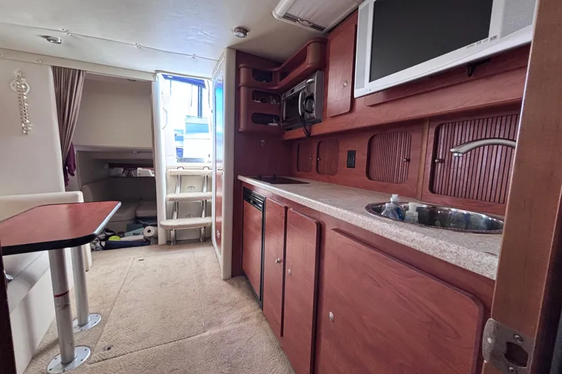 Slide: The Image of Interior of a 2007 Rinker EX 370 boat featuring a kitchenette and dining area. - 12