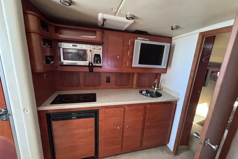 Slide: The Image of 2007 Rinker EX 370 boat interior kitchen with microwave, sink, and TV. - 13