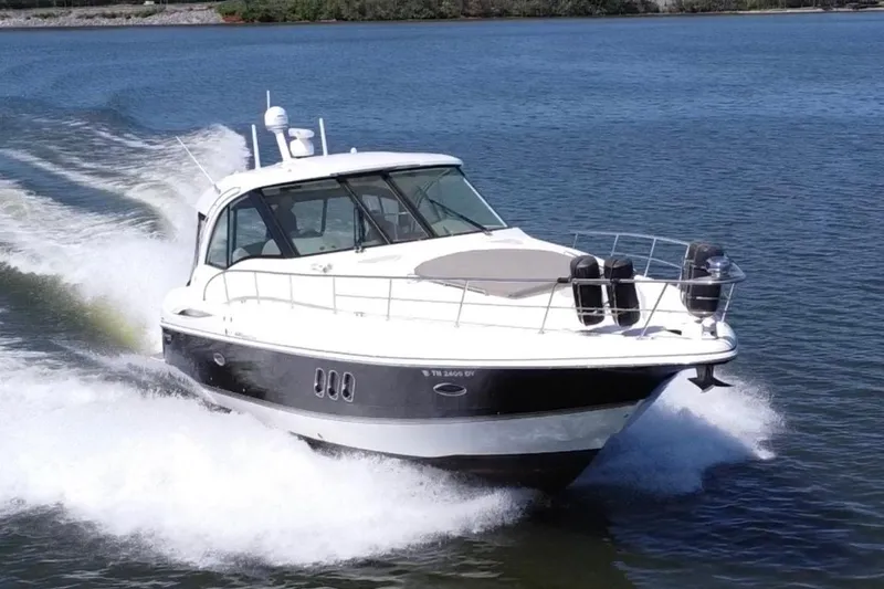 The Image of 2009 Cruisers Yachts 420 Sports Coupe speeding on a serene lake. - 0