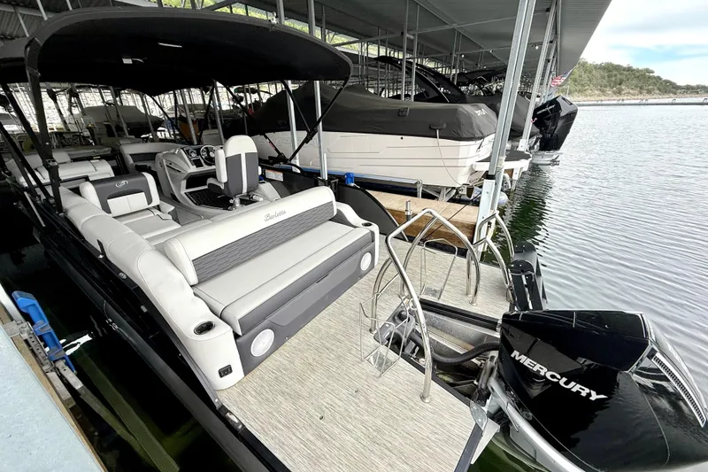 Slide: The Image of 2023 Barletta Corsa 23U pontoon boat docked, featuring spacious seating and Mercury engine. - 11