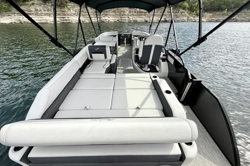Slide: The Image of 2023 Barletta Corsa 23U pontoon boat interior with seating and helm on a lake. - 13