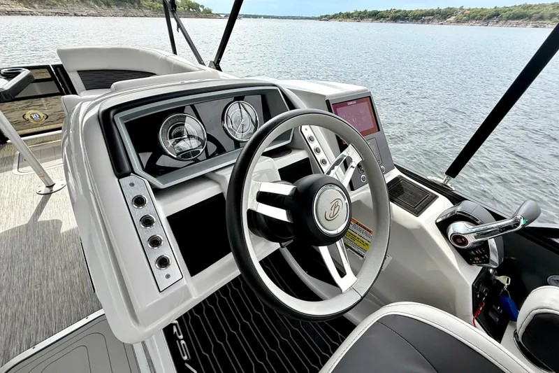 Slide: The Image of 2023 Barletta Corsa 23U boat dashboard with steering wheel and controls on a lake. - 21