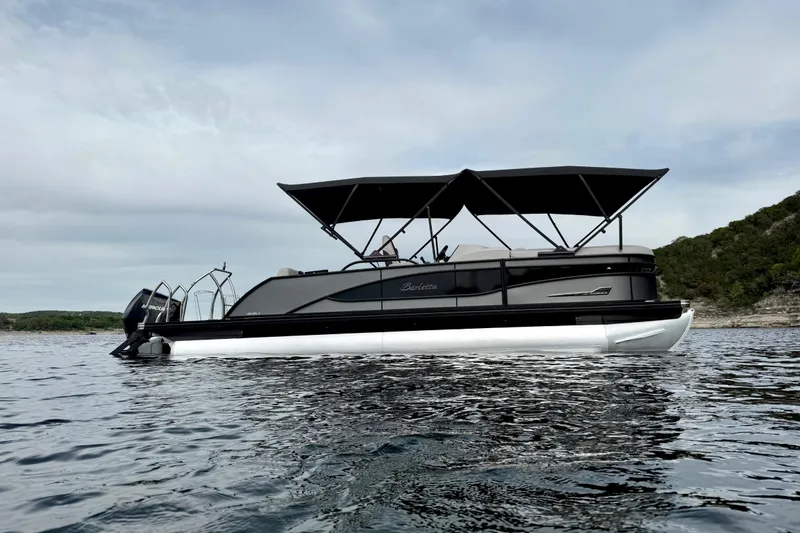 Slide: The Image of 2023 Barletta Corsa 23U pontoon boat on calm water, featuring sleek design and canopy. - 3