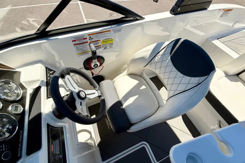 Slide: The Image of 2023 Bayliner DX 2050 boat interior with steering wheel and cushioned seat. - 16