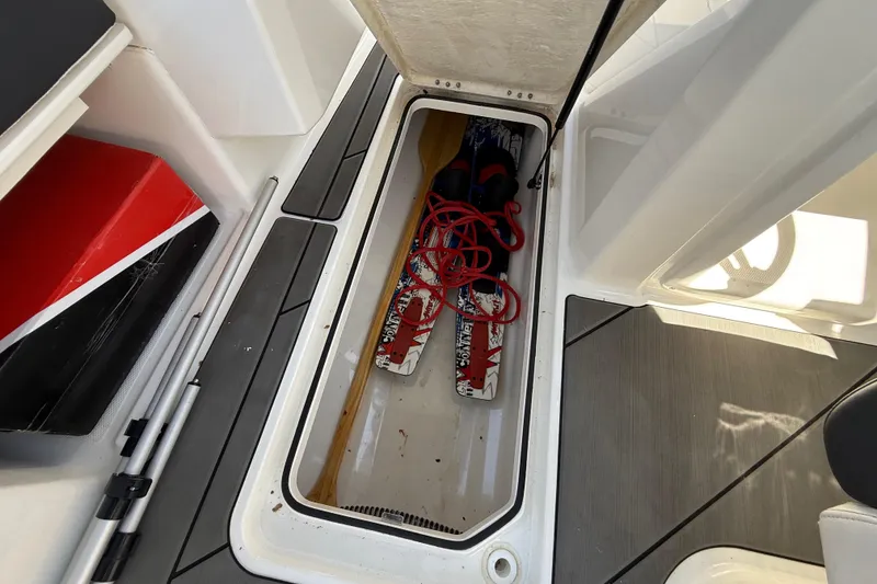 Slide: The Image of 2023 Bayliner DX 2050 boat storage compartment with water skis and red rope. - 19