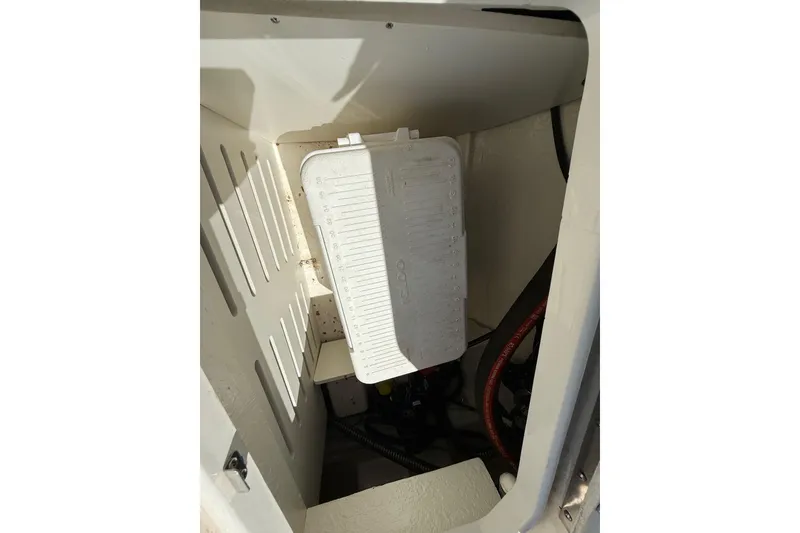 Slide: The Image of 2023 Bayliner DX 2050 boat storage compartment with white interior and visible wiring. - 20