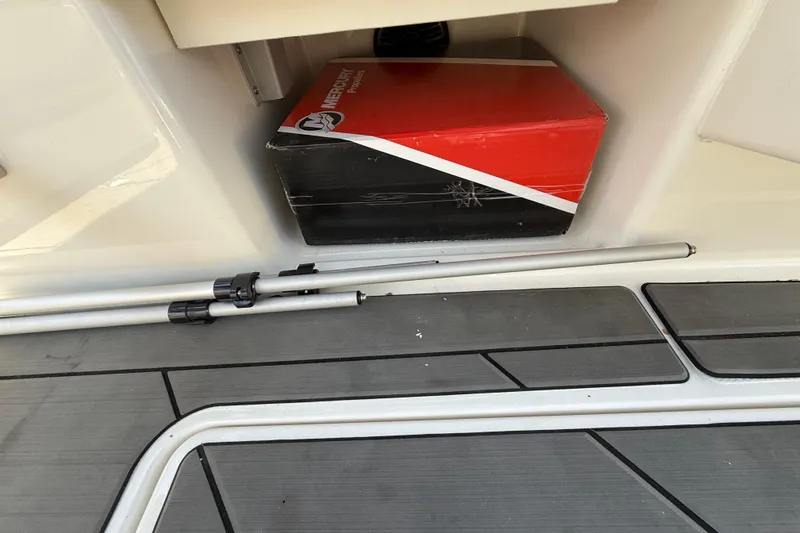 Slide: The Image of Storage compartment in a 2023 Bayliner DX 2050 boat with Mercury box and poles. - 23