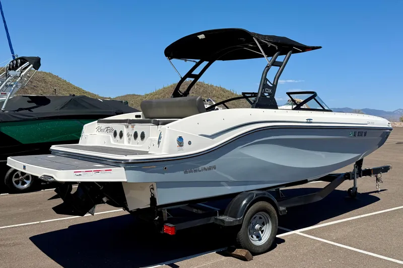 Slide: The Image of 2023 Bayliner DX 2050 boat on trailer, parked outdoors under clear blue sky. - 3