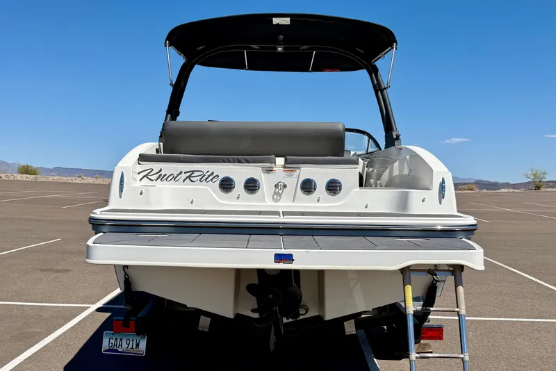 Slide: The Image of 2023 Bayliner DX 2050 boat, rear view, parked on asphalt under clear blue sky. - 5
