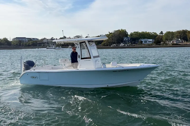 Slide: The Image of 2018 Sea Hunt Ultra 235 SE boat cruising on a calm lake with scenic shoreline. - 17