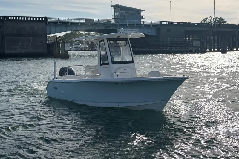 Slide: The Image of 2018 Sea Hunt Ultra 235 SE boat on water near a bridge. - 18