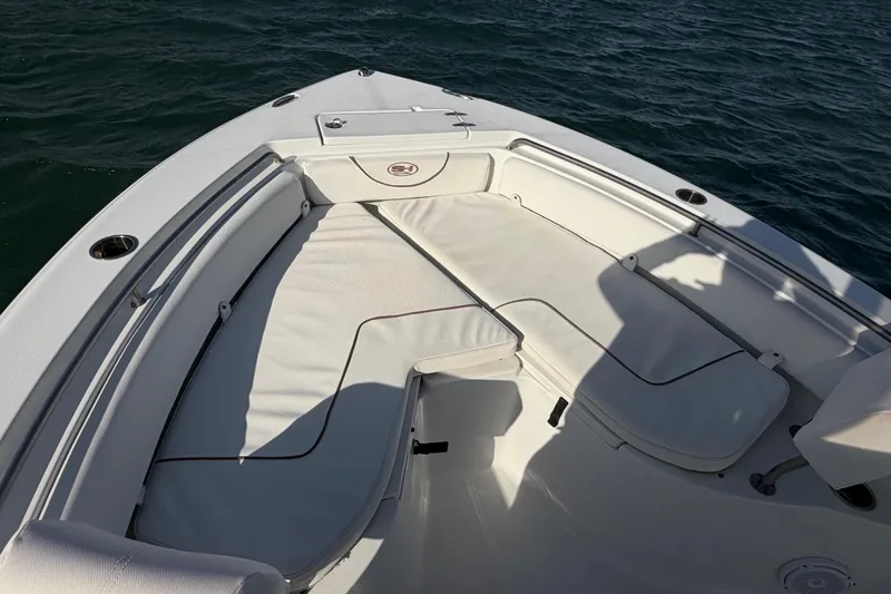 Slide: The Image of 2018 Sea Hunt Ultra 235 SE boat interior with cushioned seating on calm water. - 21